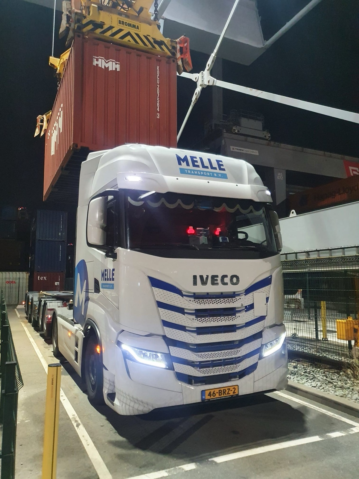 Een zeecontainer wordt 's nachts op het chassis van een Melle Transport truck geladen