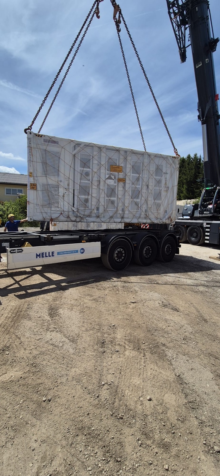 Een zware unit wordt met een telekraan op het chassis van Melle Transport geladen